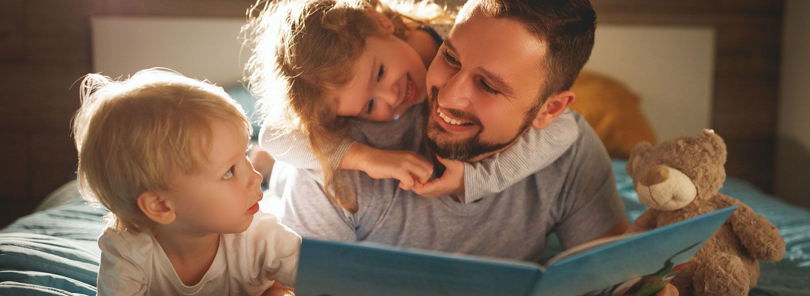 Junge Familie mit Fotobook und Teddybär